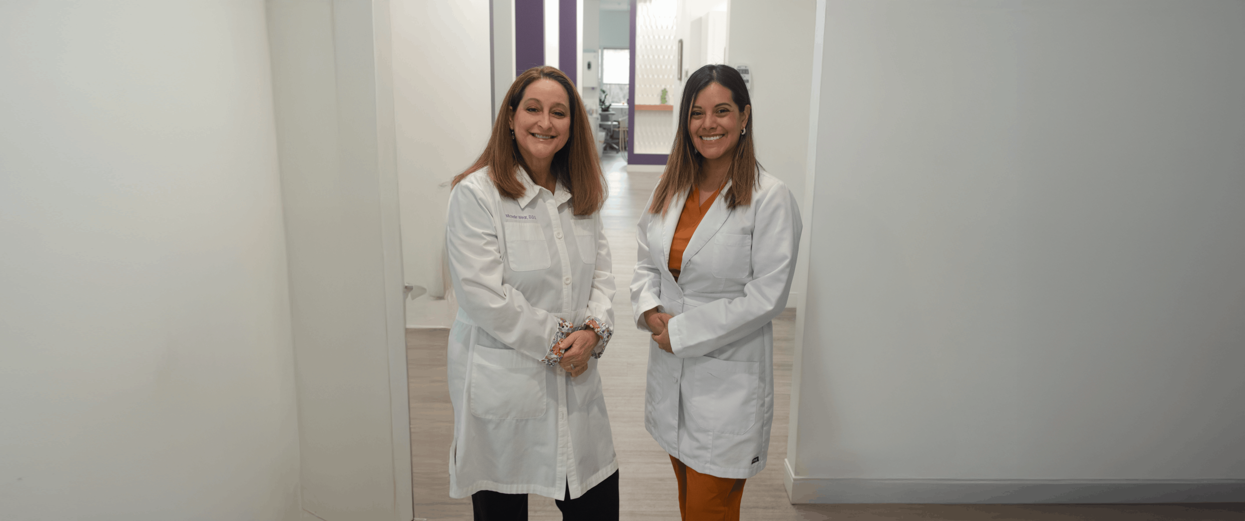 Two dentists in Frederick standing with arms crossed and smiling, conveying confidence and approachable care